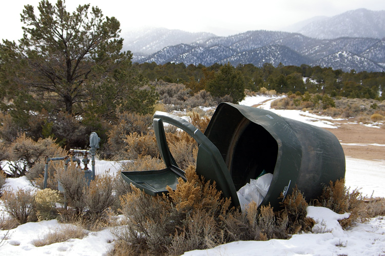 A dumpster lies tipped over by the wind...