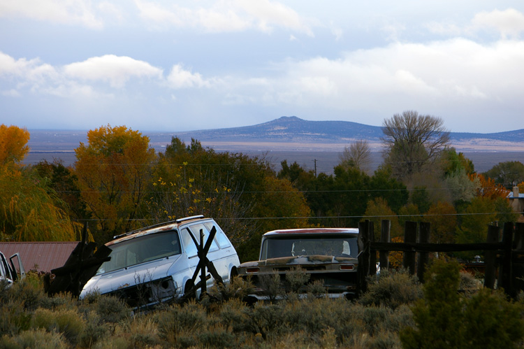 Junk cars and a distant volcano in Taos, New Mexico