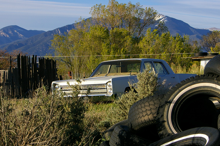 Dead car, tires, spring trees, and The Mountain.